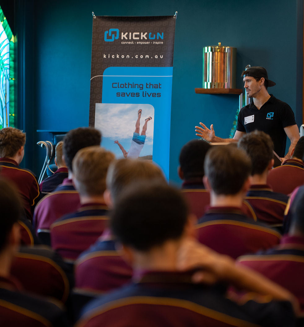 Person giving a presentation in front of an audience with a 'KICKON' banner in the background.