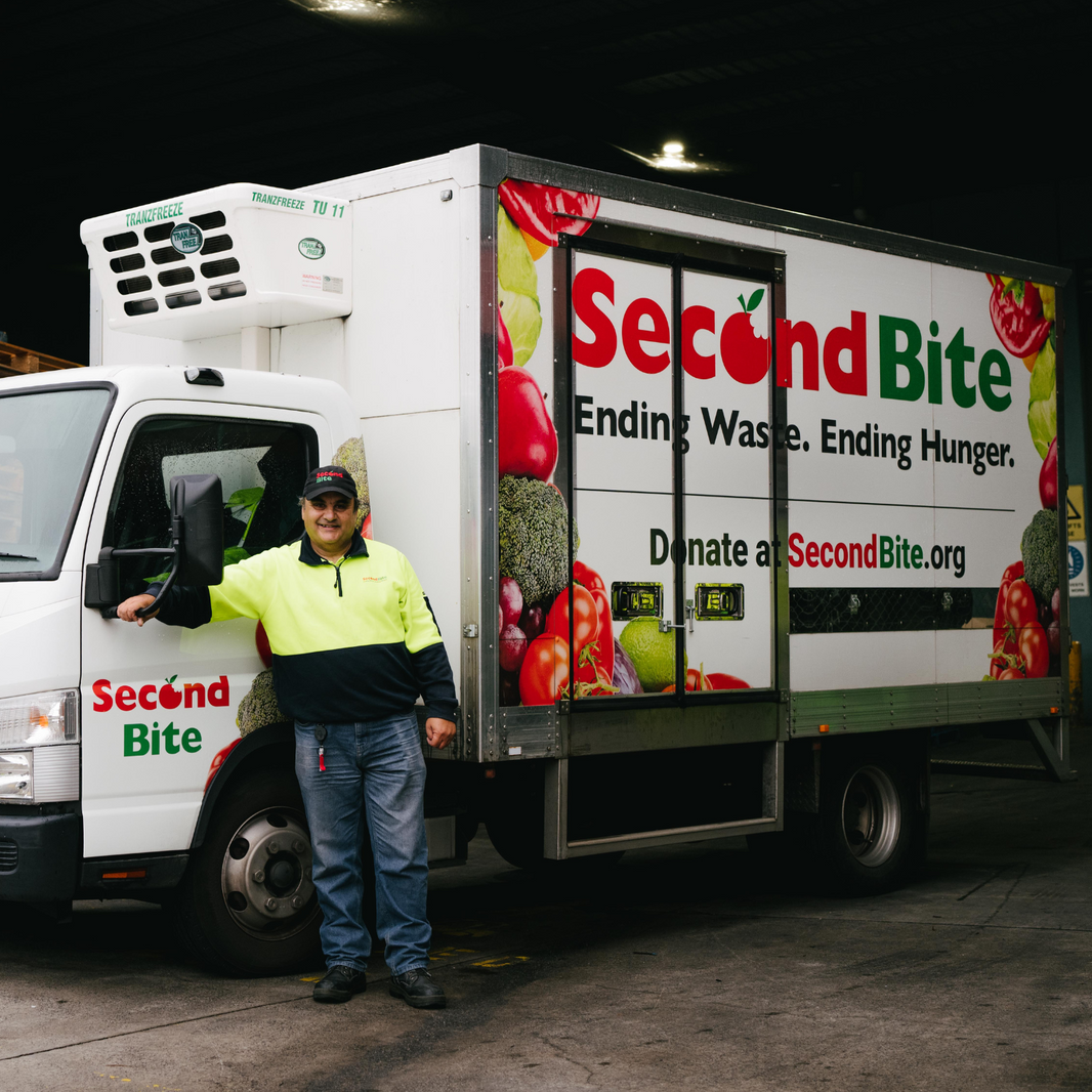 Person standing next to a 'Second Bite' truck in a warehouse setting