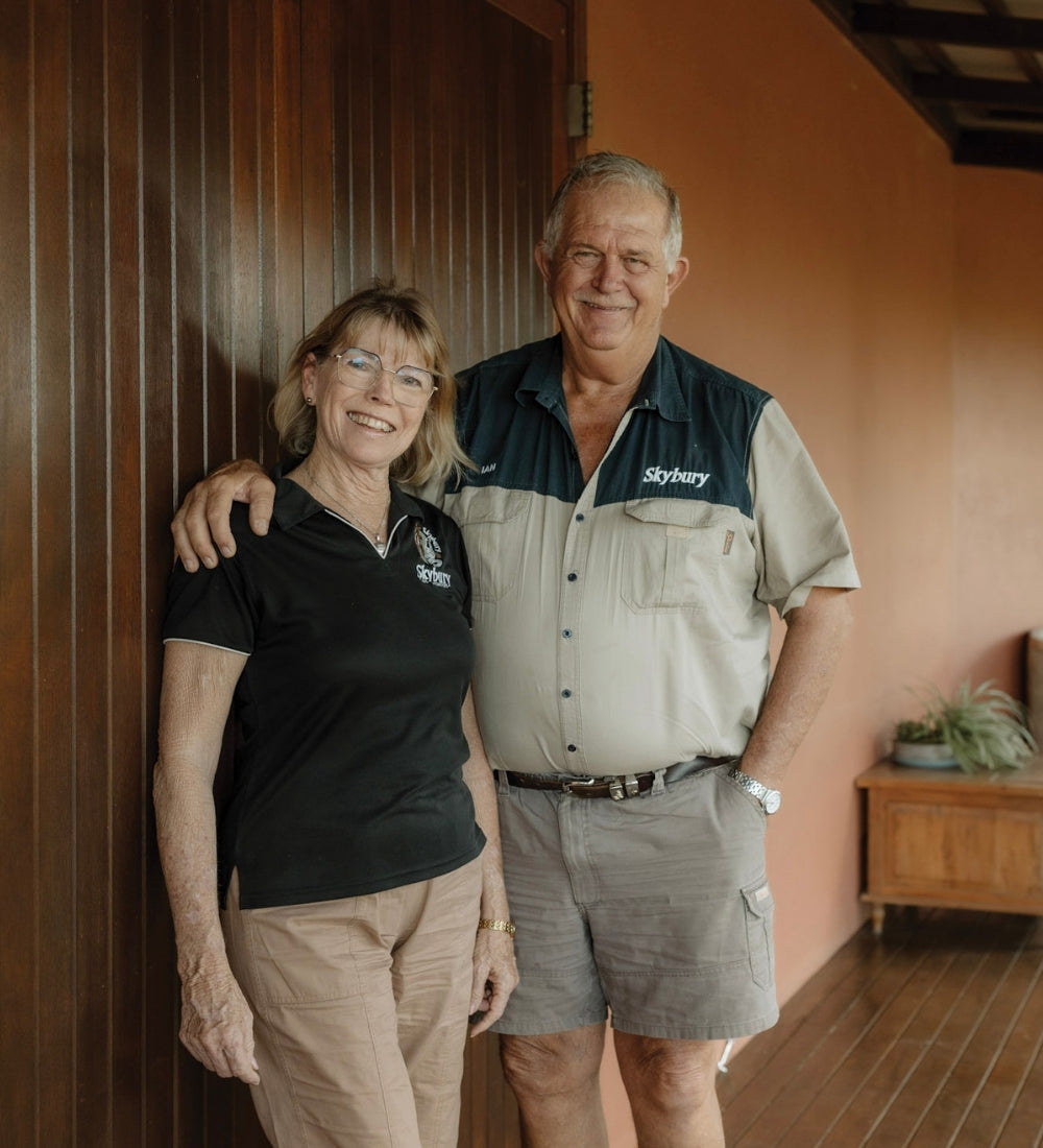 The owners of Skybury standing together, one wearing a black shirt with a logo and the other in a beige and navy uniform.